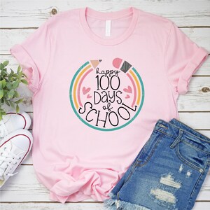 May include: Pink t-shirt with a colorful graphic that says "happy 100 days of school" with hearts and a rainbow design.
