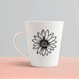 May include: A white ceramic mug with a black and white daisy design. The mug has a handle and a tapered shape.