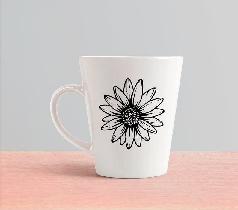 May include: A white ceramic mug with a black and white daisy design. The mug has a handle and a tapered shape.