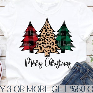 May include: A white t-shirt with three Christmas trees in red and black buffalo plaid, leopard print, and green and black buffalo plaid. The text "Merry Christmas" is printed below the trees.