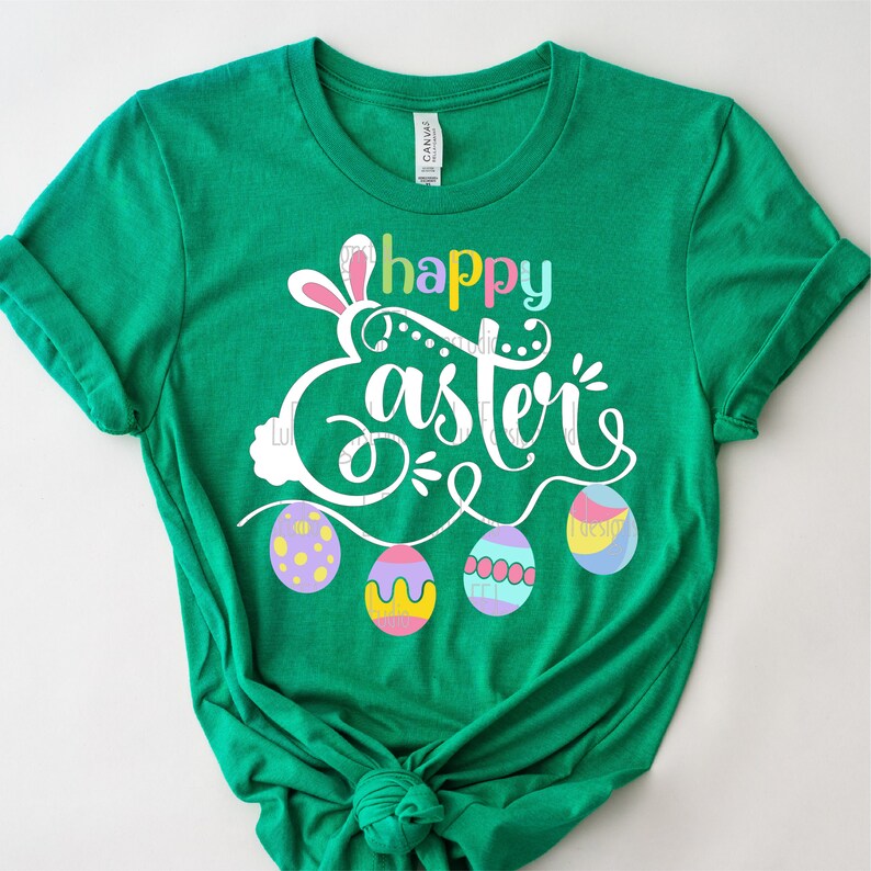 May include: Green t-shirt with a white graphic that says "Happy Easter" with bunny ears and colorful Easter eggs.