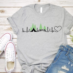 Op de afbeelding: Een grijs T-shirt met een zwart en groen ontwerp van een hartslag met een tent en bomen. De tekst "camp life" is in het ontwerp opgenomen.