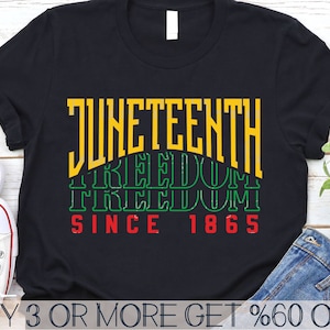 Puede incluir: Camiseta negra con el texto "JUNETEENTH FREEDOM SINCE 1865" en letras amarillas, verdes y rojas.