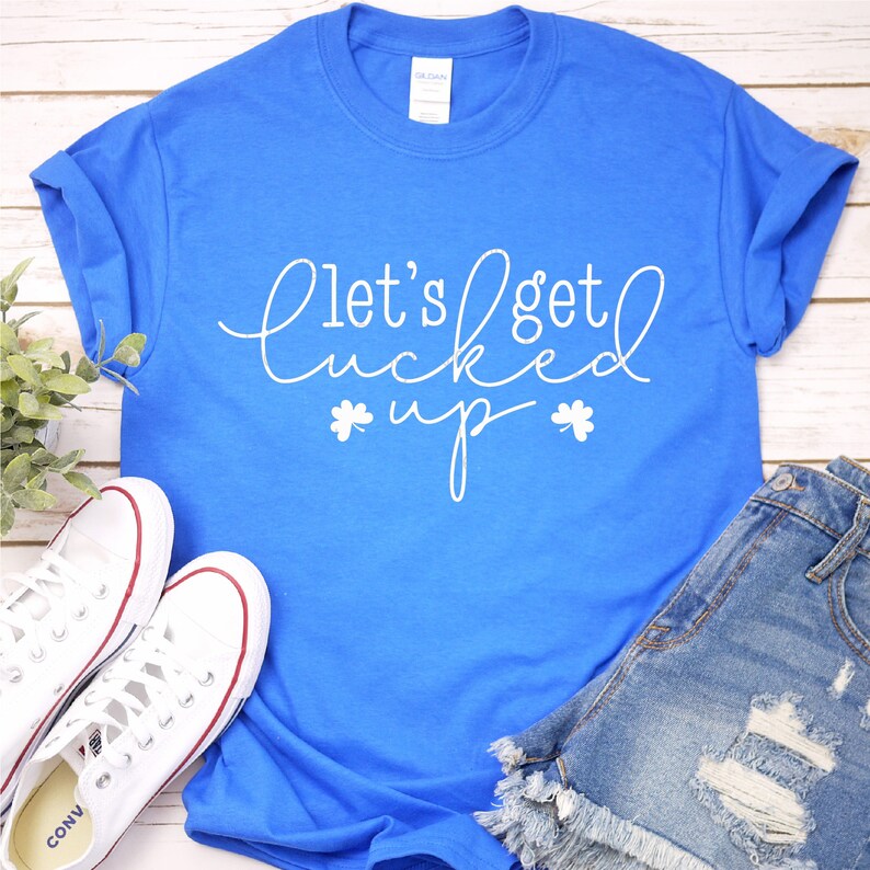 May include: A royal blue t-shirt with the text "Let's get lucked up" in white with shamrock symbols on either side of the word "up".