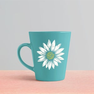 Op de afbeelding: Een teal keramische mok met een wit madeliefje ontwerp. De madeliefje heeft een gele kern met een luipaardprint.