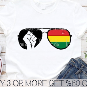 Puede incluir: Una camiseta blanca con una imagen en blanco y negro de un puño con gafas de sol. Las gafas de sol tienen un diseño rojo, amarillo y verde en la lente derecha.