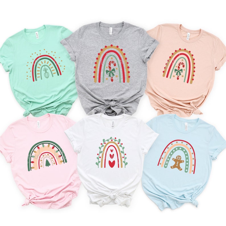 May include: Six different Christmas-themed rainbow t-shirts in various colors. Each shirt features a different design, including a candy cane, a Christmas tree, a gingerbread man, and hearts.