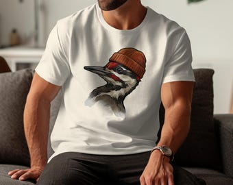 May include: White t-shirt featuring a detailed illustration of a Pileated Woodpecker wearing a brown beanie. The bird has a black and white body with a red crest. The shirt is a casual, everyday wear item.