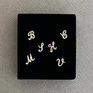 May include: A black velvet box with gold letters on a black background. The letters are B, S, H, M, C, and V.