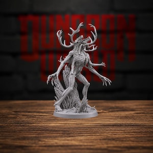 May include: A grey, unpainted miniature figurine of a multi-limbed creature with a deer-like skull, large branching antlers, and a skeletal, muscular physique. The figure stands on a circular base, featuring textured details and sharp claws.