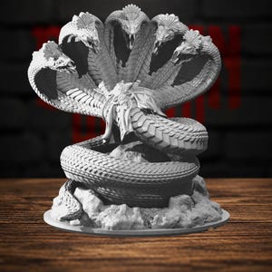 Può includere: Una statuetta in resina grigia non dipinta raffigurante un serpente cobra a più teste. La scultura presenta cinque teste di serpente distinte con cappucci aperti, trame di squame dettagliate e un corpo avvolto su una base rocciosa irregolare.