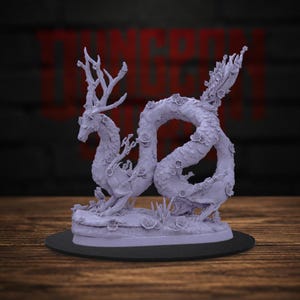 May include: A light purple miniature figurine of a serpentine creature with deer-like antlers and a long, winding body. The creature is adorned with small sculpted flowers along its back and tail, standing on a circular base with floral details.