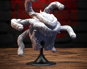 May include: A white, unpainted miniature figurine of a multi-eyed creature with a central body, numerous tentacles extending outward, and a wide, toothy maw. The creature is mounted on a simple black circular stand, displaying intricate textures.
