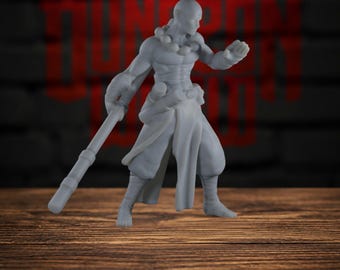 以下が含まれることがあります： 頭を剃った武道家のキャラクターの、塗装されていないライトグレーのミニチュアフィギュア。数珠のネックレス、ゆったりとしたズボン、前腕に巻物を身につけ、片手に長い杖を持ち、もう一方の手を前に突き出している姿が表現されています。