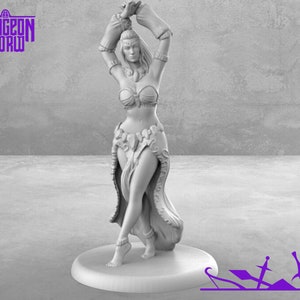 May include: A white figurine of a woman in a flowing skirt and a jeweled top, with her arms raised above her head. She is posed in a dancing position, with one leg slightly raised. The figurine is set on a round base.
