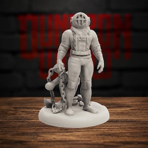 May include: A light gray miniature figurine of a deep-sea diver wearing a vintage-style helmet with a protective cage over the faceplate. The figure stands on a circular base, holding a large metal anchor attached to a heavy chain in one hand.