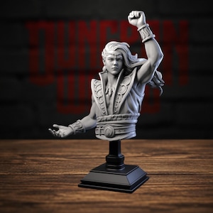 May include: A grey resin bust of a long-haired figure with a headband, wearing a high-collared vest with ornate trim and a belt. The figure has one arm raised with a clenched fist and the other arm extended outward, mounted on a black pedestal.