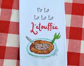 Może przedstawiać: Biały ręcznik kuchenny z akwarelową ilustracją miski z gumbó z zieloną cebulą i łyżką. Tekst "Fa La La La La L'etouffee" jest napisany czerwonym kursywą nad miską.