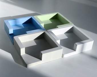 May include: Four square concrete containers with a small opening on one side. The containers are in shades of light blue, green, and white.