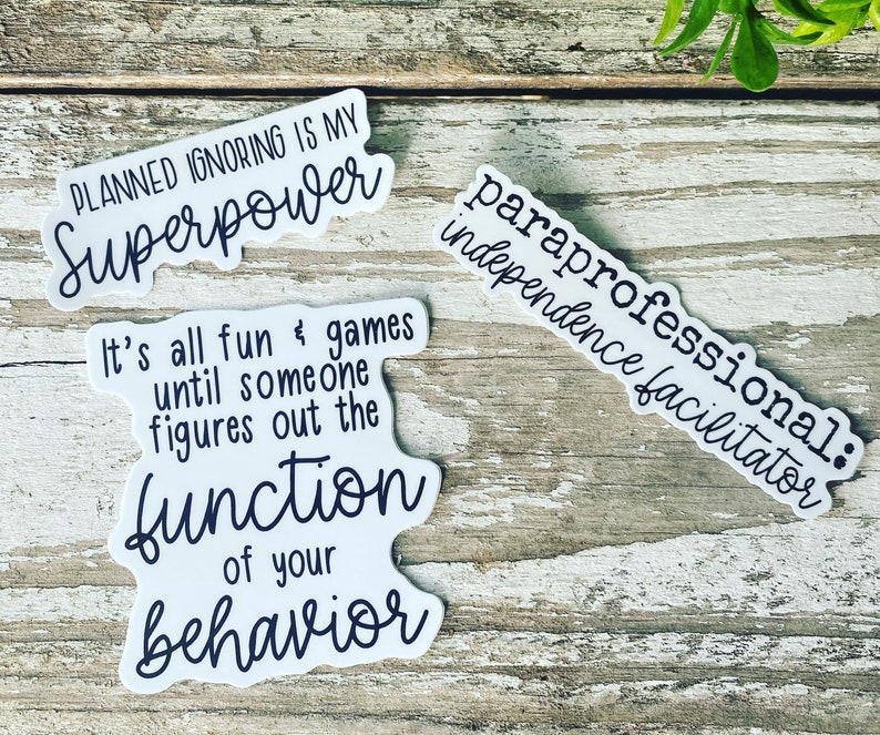 K&ouml;nnte beinhalten: Vier wei&szlig;e Aufkleber mit schwarzem Text. Die Aufkleber haben folgenden Text: "Geplantes Ignorieren ist meine Superkraft", "Es macht alles Spa&szlig; und Spiele, bis jemand die Funktion deines Verhaltens herausfindet", "Paraprofessioneller: Unabh&auml;ngigkeitsvermittler"