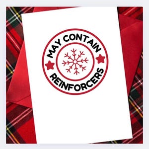 May include: A white greeting card with a red envelope, featuring a circular design with the text "MAY CONTAIN REINFORCERS" around a snowflake. The background is a red and green plaid pattern.