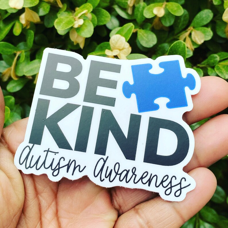 Puede incluir: Una pegatina blanca con el texto "Be Kind" en letras negras y grises. Una pieza de rompecabezas azul est&aacute; al lado de la palabra "Be". El texto "Autism Awareness" est&aacute; escrito en cursiva debajo de las palabras "Be Kind".