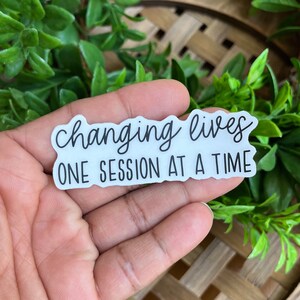 May include: White sticker with black text that reads "Changing lives one session at a time".