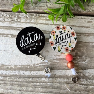 May include: Two black and white badge reels with the text "data or it didn't happen" and a line graph. One reel has a floral design with pink and white flowers.