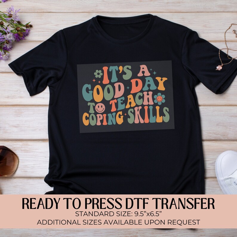 May include: Ready to press DTF transfer design on a black t-shirt. The design features a retro-style font with the text "It's a good day to teach coping skills".