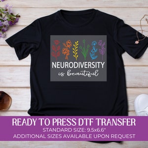 May include: A black t-shirt with a gray square design featuring a rainbow of flowers and the text "Neurodiversity is beautiful". The shirt is a ready-to-press DTF transfer, standard size 9.5x6.6 inches.