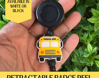 Puede incluir: Carrete de identificación retráctil con un amuleto de autobús escolar amarillo. El carrete es negro y tiene un botón negro. El amuleto tiene las palabras "School Bus" en él. Disponible en blanco o negro.