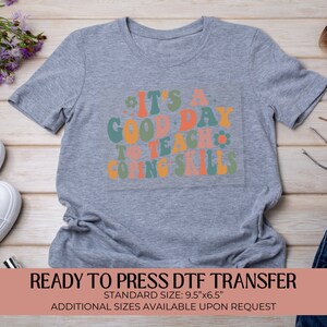 May include: Gray t-shirt with a colorful graphic that reads "It's a good day to teach coping skills". The graphic is in a retro style with flowers and smiley faces. The shirt is ready to press with a DTF transfer. Standard size is 9.5 inches by 6.5 inches. Additional sizes are available upon request.