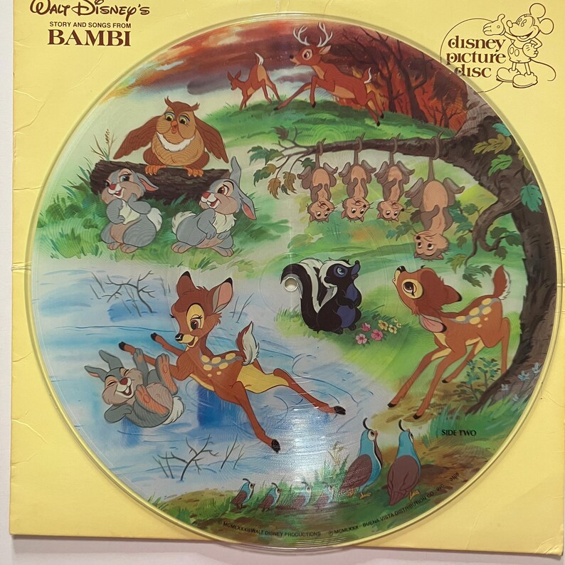 May include: A vintage Disney picture disc featuring characters from the animated film "Bambi." The disc showcases colorful illustrations of Bambi, Thumper, Flower, and other forest animals in a woodland scene. The disc is labeled "Side Two."