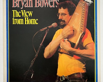 May include: A vinyl record album cover featuring a man playing a dulcimer. The album is titled "The View from Home" by Bryan Bowers.