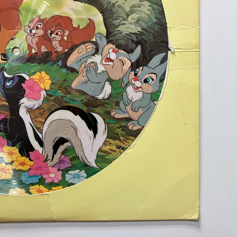 May include: A vintage illustration featuring animated forest animals. The image includes a skunk, rabbits, and squirrels, set against a backdrop of flowers and trees. The artwork has a classic, nostalgic feel, with vibrant colors and detailed character designs.