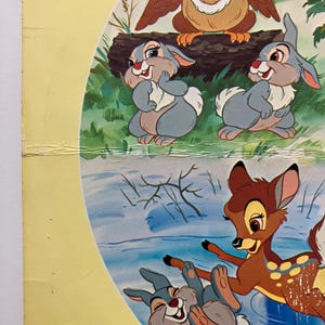May include: A colorful illustration featuring characters from the animated film Bambi. The image includes a brown owl, gray rabbits, and a brown deer with white spots, set against a backdrop of a forest and water.