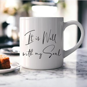 May include: White ceramic mug with a black inscription that reads "It is Well with my Soul".