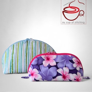 May include: Two zippered cosmetic bags. One is blue and white striped, the other has a purple and pink floral print. The bags are on a white surface.  my cup of stitching