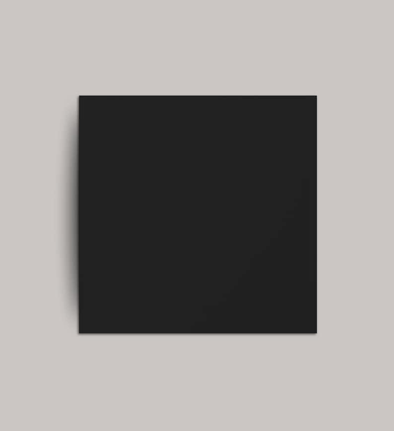 May include: A solid black square against a light gray background. The square is centered and takes up most of the frame, with a slight shadow on the left side, suggesting depth.