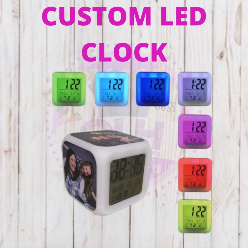 Pode incluir: Um rel&oacute;gio LED branco com uma moldura de fotos personaliz&aacute;vel. O mostrador do rel&oacute;gio exibe a hora, a data e a temperatura. O rel&oacute;gio &eacute; cercado por rel&oacute;gios menores de v&aacute;rias cores, cada um mostrando a hora "1:22".