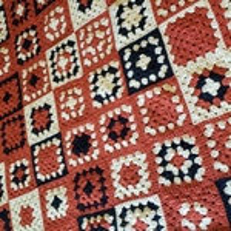May include: A crocheted blanket with a patchwork design in shades of red, white, and black.