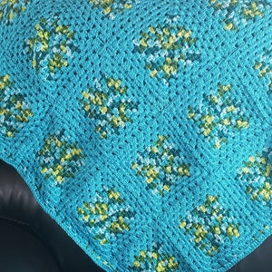 May include: A crocheted blanket with a diamond pattern in shades of turquoise, green, and white.