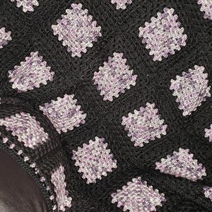 May include: A black crocheted blanket with a repeating pattern of purple and white squares.