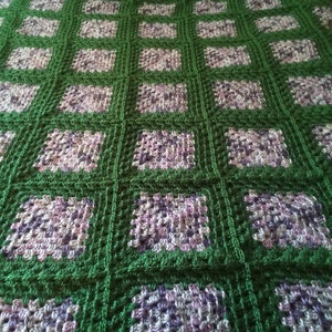 May include: A green and purple crocheted blanket with a square pattern.
