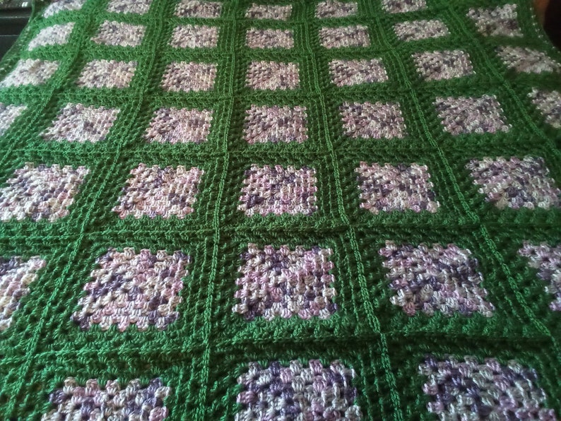 May include: A green and purple crocheted blanket with a square pattern.