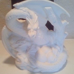 Pode incluir: Estatueta de dragão de cerâmica branca com escamas, asas e cauda enrolada detalhadas. O dragão está empoleirado em uma base com uma estrutura semelhante a uma árvore, criando uma escultura com tema de fantasia.