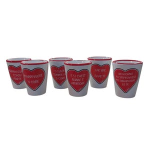 May include: Six white ceramic shot glasses with red rims and red hearts. Each glass has a different Italian phrase printed on it.