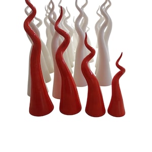 Può includere: Una collezione di sculture in vetro di colore rosso e bianco. Le sculture hanno la forma di corna contorte e a spirale.
