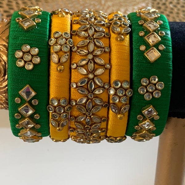 green and yellow5 piece reshmi silk thread bangle set has 3 medium width and 2 thin width bangles.beautiful stone and kundan work.size 2.8