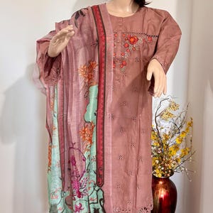 Op de afbeelding: Een roze en groene dupatta met een bloemenprint en een roze geborduurde kurta. De kurta heeft een ronde hals en 3/4 mouwen. De dupatta heeft een gegolfde rand.